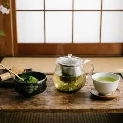 Préparation d'un thé vert japonais. Poudre de matcha, fouet, théière en verre fumante et tasse invitent à découvrir quel est le meilleur thé vert.