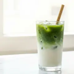 Un verre de matcha latte glacé avec une paille en bambou, parfait pour savourer son goût unique.