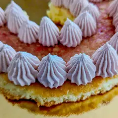 Gâteau orné de rosaces de ganache chocolat blanc framboise sur un lit de fruits rouges.