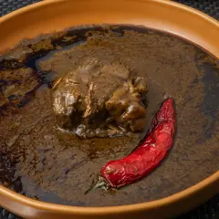 Un plat de mloukhia égyptienne, un ragoût de viande savoureux, servi avec un piment rouge séché dans un bol en terre cuite.