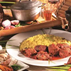 Un rougail saucisses traditionnel, servi avec du riz jaune, des tomates, des oignons et des épices.