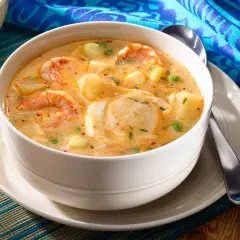 Un bol de chupe de camarones crémeux, garni de crevettes, pommes de terre et petits pois.