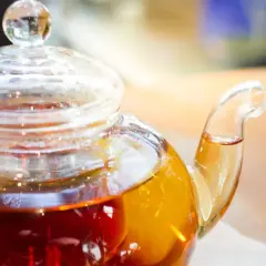 Thé ambré dans une théière en verre, prêt à être servi. La question est : combien d'eau pour un sachet de thé ?
