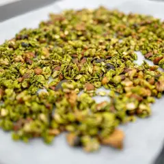 Granola claire au matcha, parsemée d'amandes et de graines, prête à être cuite sur une plaque de cuisson.