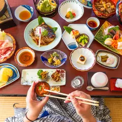 Un festin de street food japonais : sashimi, poisson grillé, tofu, et bien plus encore, présenté avec art sur une table en bois.