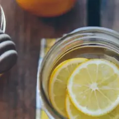 Un verre rempli de rondelles de citron, prêt à recevoir du miel et de la cannelle pour ses bienfaits.
