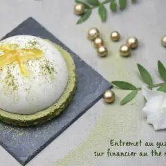 Un entremet yuzu aérien, saupoudré de matcha, repose sur un financier au thé matcha. Décoré de zestes de yuzu confits.