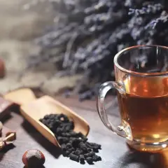 Un thé ambré dans une tasse, du chocolat, des noisettes et des feuilles de thé. Idéal pour le temps conservation thé infusé.