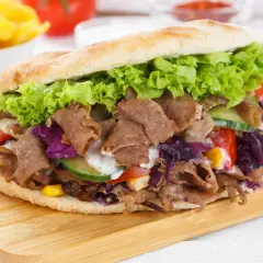 Un généreux kebab maison garni de viande, salade, tomates, concombre et chou rouge, prêt à être dégusté.