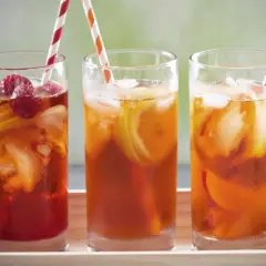 Trois verres de thé vert glacé, garnis de fruits rouges et de citron, prêts à être dégustés.