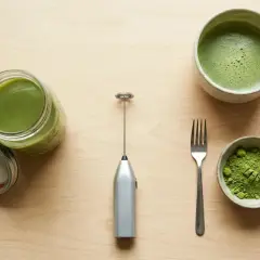 Préparation du matcha sans fouet : poudre verte, boisson mousseuse dans un bol, et un petit appareil argenté pour mélanger.