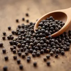 Une cuillère en bois déborde de grains de poivre noir, posée sur une surface en bois. Le poivre est-il bon pour la santé ? Ces petites baies pourraient bien l'être.