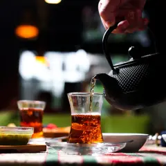 Une main verse du thé ceylan bienfait dans un verre. Ambiance chaleureuse et réconfortante.