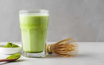 Un verre de matcha crémeux, une cuillère de poudre verte et un fouet traditionnel. Idéal pour une femme enceinte cherchant une boisson saine.