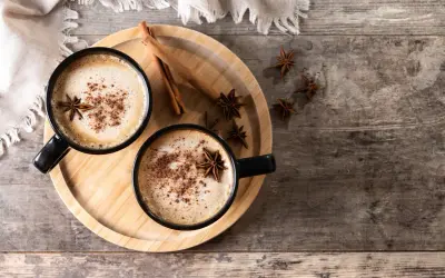Deux tasses de chai latte réconfortant, garnies d'anis étoilé et de cannelle, sur un plateau en bois.