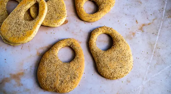 Plusieurs kaaks libanais dorés, saupoudrés de graines de sésame, sont disposés sur une surface claire.