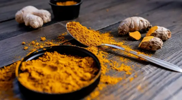 Poudre de curcuma et racines sur fond de bois. Le curcuma est connu pour ses nombreux cumin bienfaits.