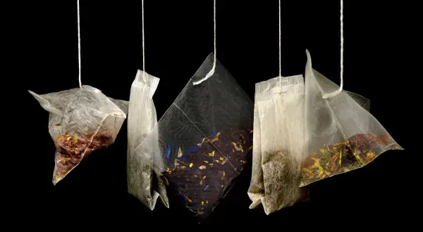 Cinq sachets de thé suspendus, révélant des mélanges variés de marc de thé et de fleurs séchées.