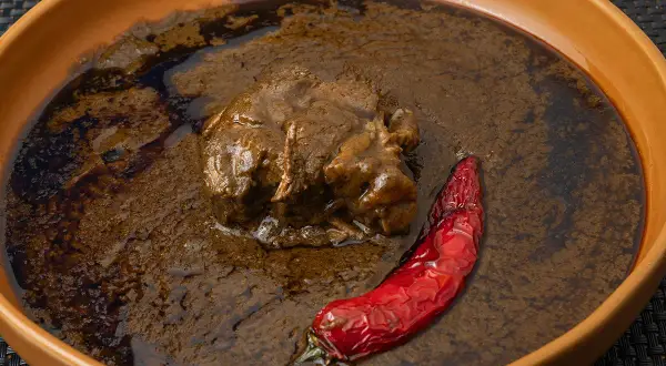 Un plat de mloukhia égyptienne, un ragoût de viande savoureux, servi avec un piment rouge séché dans un bol en terre cuite.