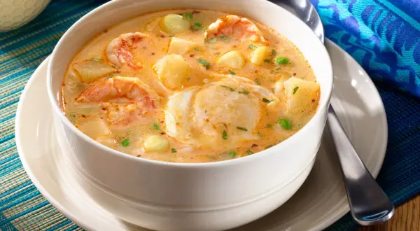 Un bol de chupe de camarones crémeux, garni de crevettes, pommes de terre et petits pois.