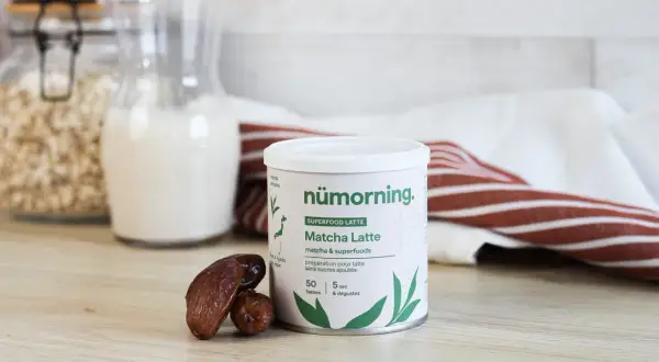 Boîte de matcha latte, idéal pour le matcha pour maigrir. Des dattes et des flocons d'avoine complètent cette scène saine.