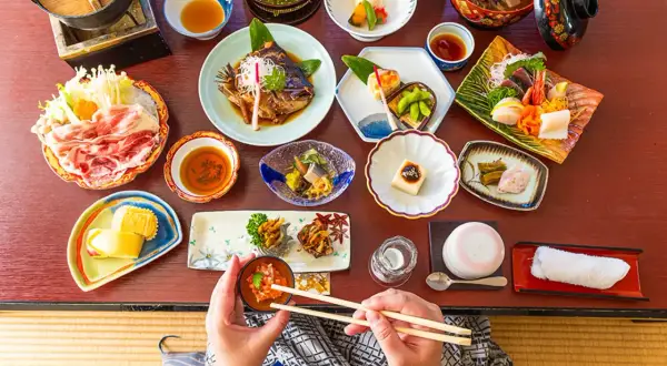 Un festin de street food japonais : sashimi, poisson grillé, tofu, et bien plus encore, présenté avec art sur une table en bois.