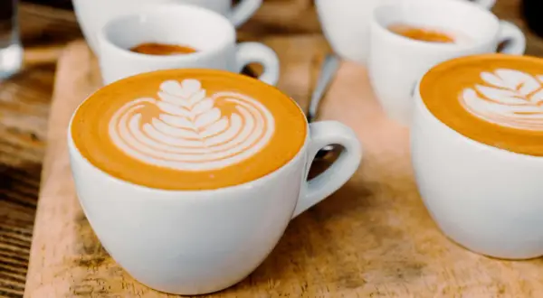 Tasses de café au lait avec une belle latte composition, sur fond de bois.