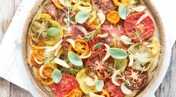 Tarte tomate claire au matcha, garnie de tomates multicolores, oignons, ail, romarin et basilic frais. Une œuvre culinaire colorée et savoureuse.