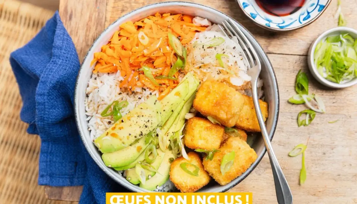 Bol coloré avec riz, carottes râpées, avocat et cubes de tofu teriyaki croustillants, garni de ciboule.