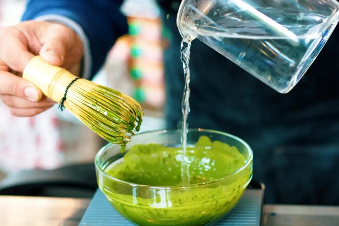 Préparation d'un matcha apaisant pour l'intestin irritable. Un fouet en bambou est utilisé pour mélanger la poudre verte dans un bol.