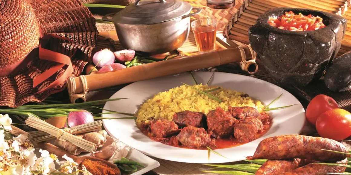 Un rougail saucisses traditionnel, servi avec du riz jaune, des tomates, des oignons et des épices.