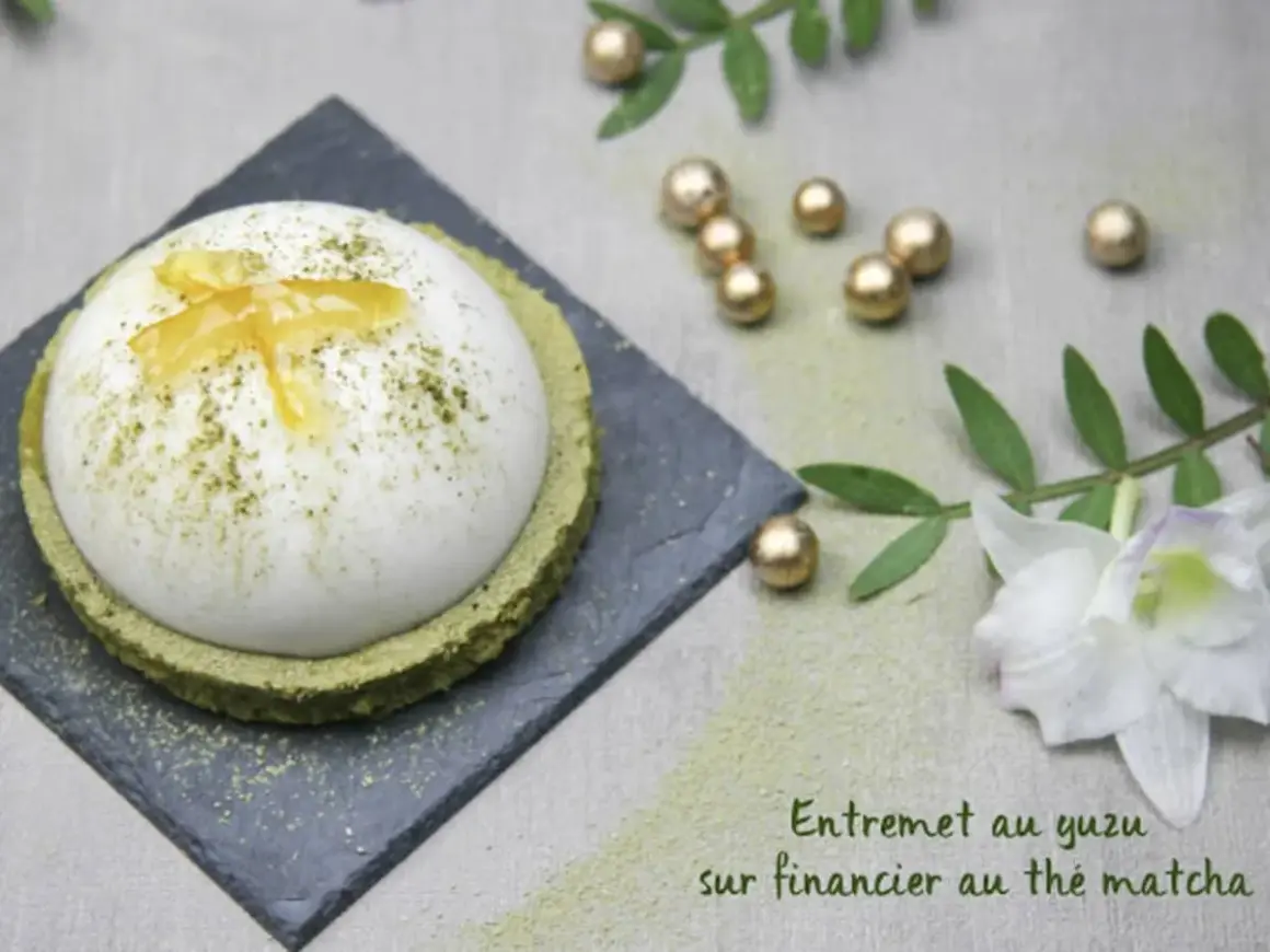 Un entremet yuzu aérien, saupoudré de matcha, repose sur un financier au thé matcha. Décoré de zestes de yuzu confits.
