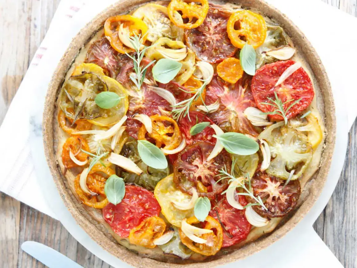 Tarte tomate claire au matcha, garnie de tomates multicolores, oignons, ail, romarin et basilic frais. Une œuvre culinaire colorée et savoureuse.