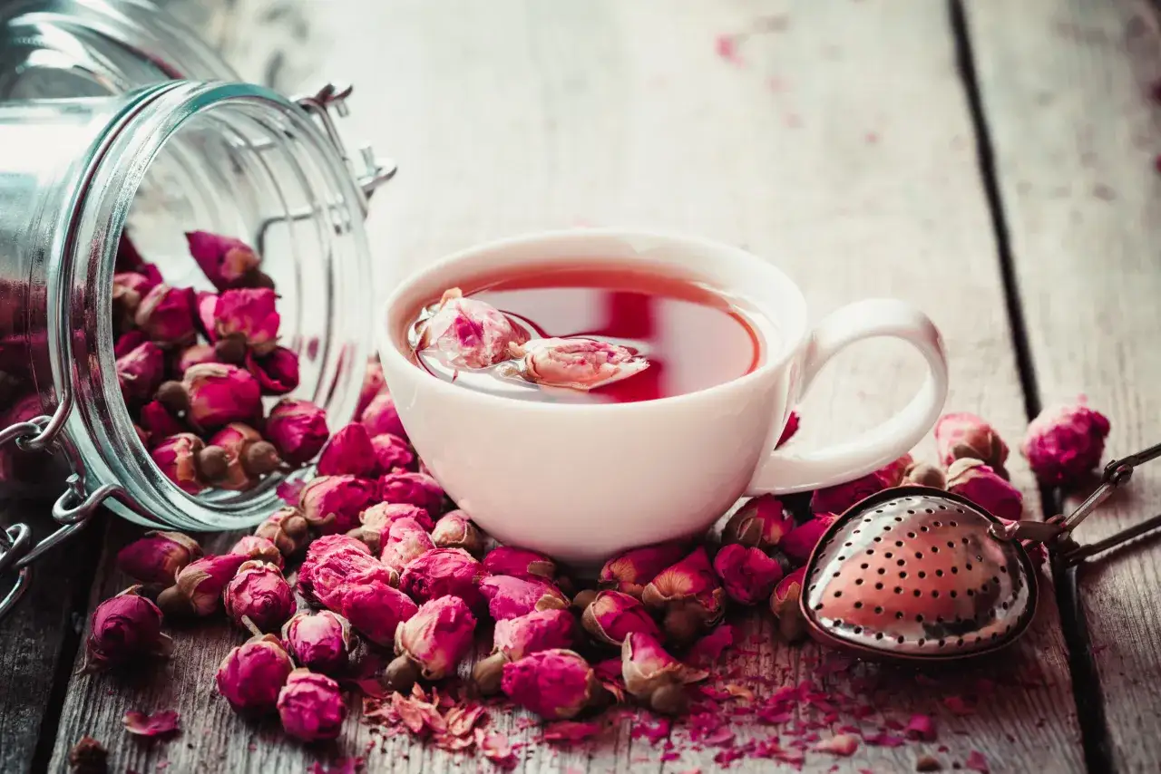 Une tasse de th&eacute; rose fumant, entour&eacute;e de boutons de rose s&eacute;ch&eacute;s. Une infusion d&eacute;licate pour un moment de d&eacute;tente.