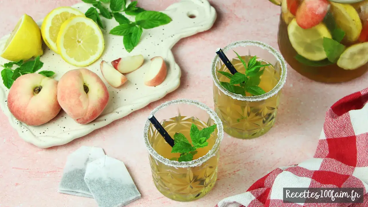 Deux verres de th&eacute; glac&eacute; maison, d&eacute;cor&eacute;s de menthe fra&icirc;che et de sucre, accompagn&eacute;s de p&ecirc;ches plates, de citrons et de sachets de th&eacute;.
