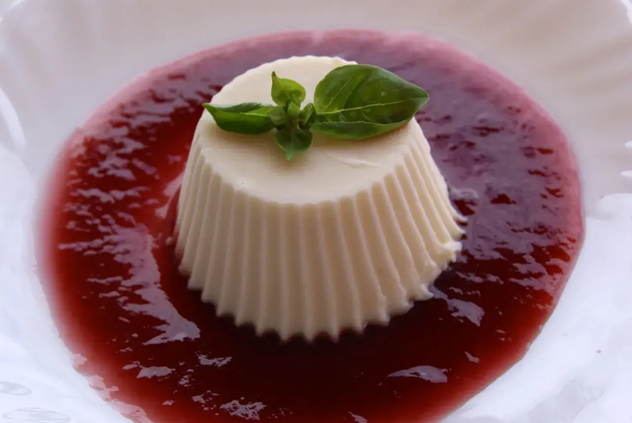 D&eacute;licieux panna cotta chocolat blanc, napp&eacute; d'un coulis de fruits rouges et garni d'une feuille de basilic.