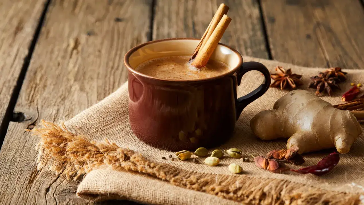 Une tasse de lait de poule fumant, garnie de bâtons de cannelle, entourée d'épices comme le gingembre et la cardamome.