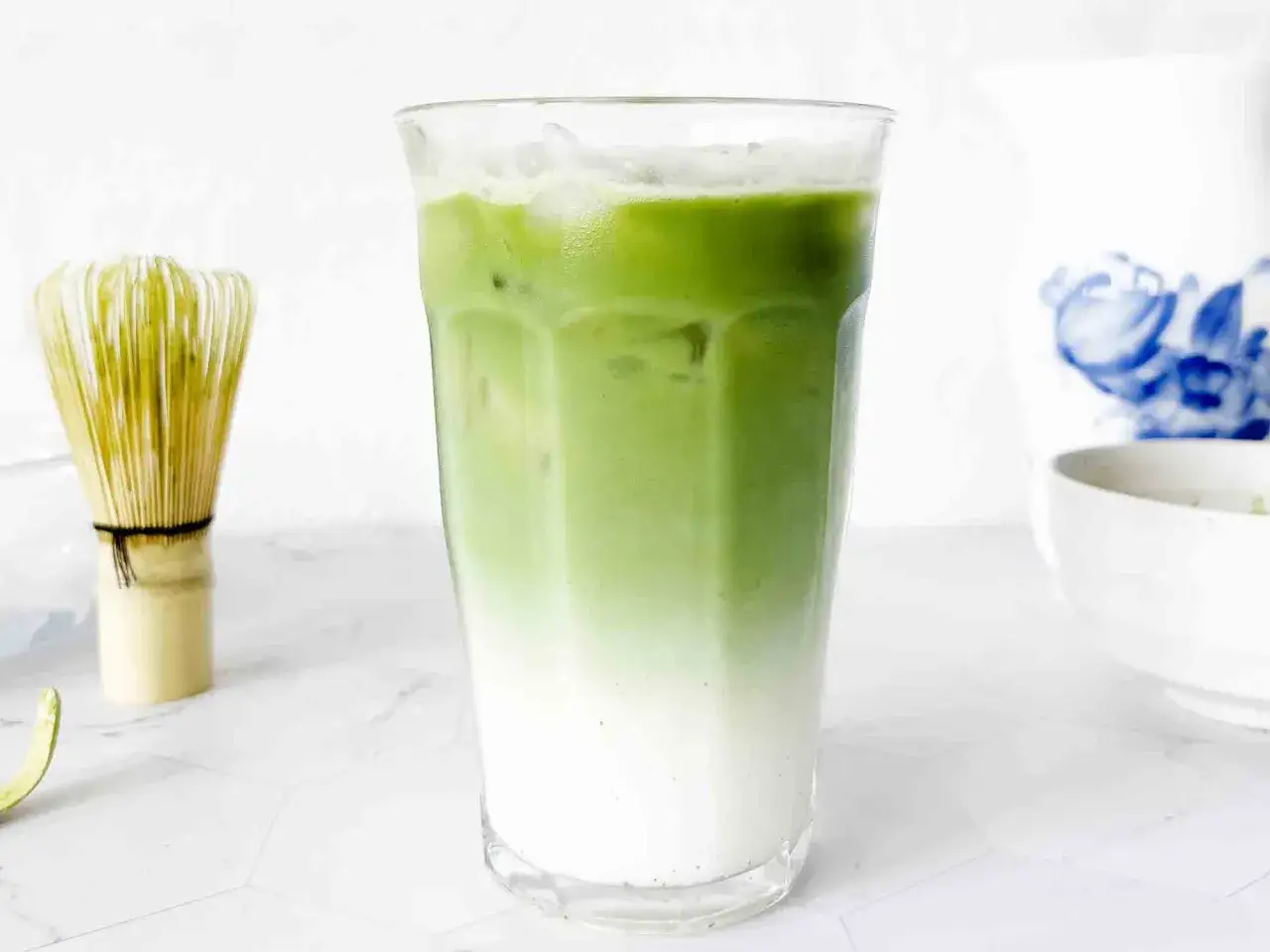 Un verre de th&eacute; matcha glac&eacute;, parfait pour savoir si on peut boire le th&eacute; matcha froid. Un fouet &agrave; matcha est visible &agrave; c&ocirc;t&eacute;.