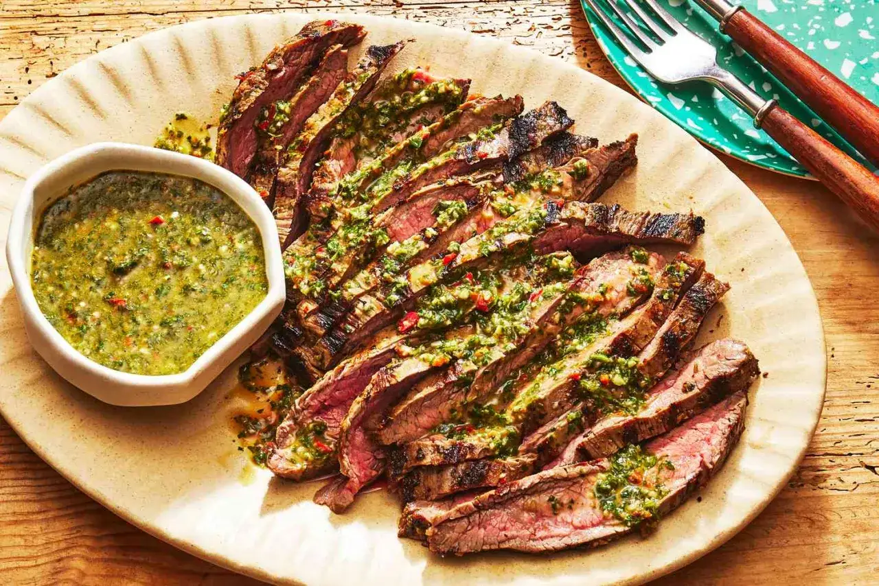 Tranches de bœuf grillé, généreusement arrosées de sauce chimichurri vibrante, servies avec une sauce d'accompagnement.
