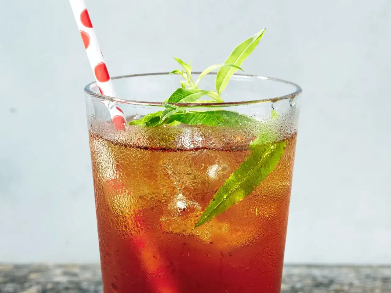 Verre de th&eacute; glac&eacute; rafra&icirc;chissant avec des feuilles vertes et une paille &agrave; pois. D&eacute;couvrez les mugicha bienfaits pour une boisson saine.