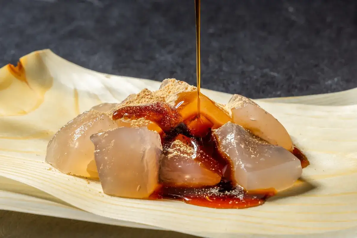 Gla&ccedil;ons translucides de warabi mochi, saupoudr&eacute;s de kinako et napp&eacute;s d'un sirop brun.