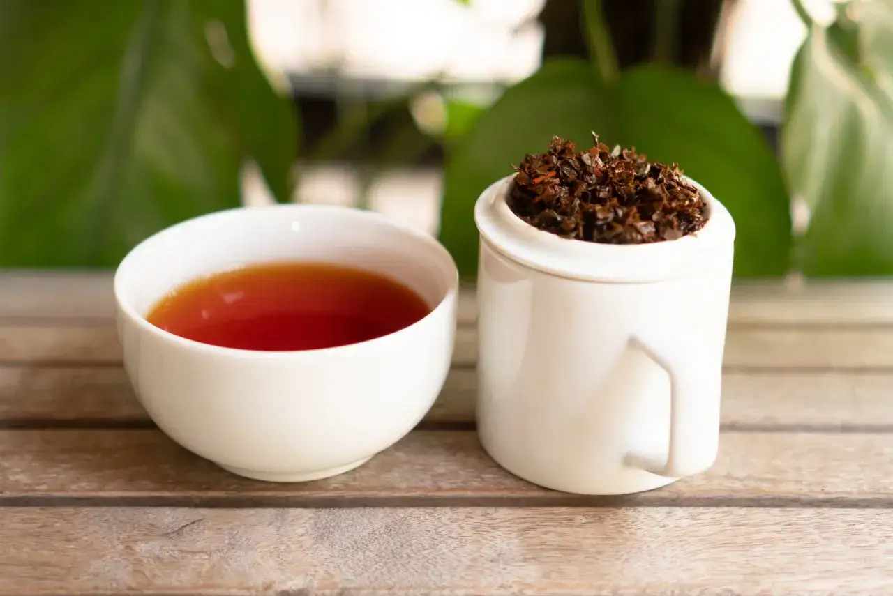 Une tasse de th&eacute; ambr&eacute; et une tasse remplie de feuilles de th&eacute; s&eacute;ch&eacute;es. Le th&eacute; ceylan bienfait pour la sant&eacute;.