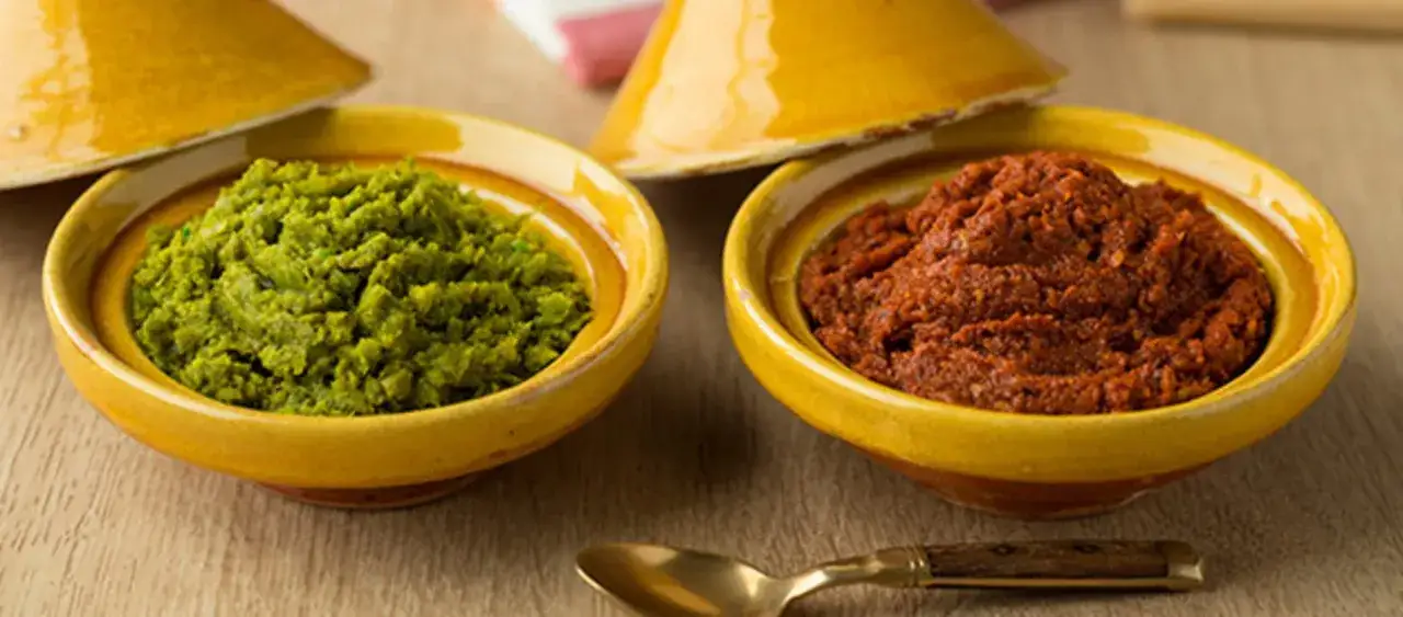 Deux bols de harissa, une verte et une rouge, pr&ecirc;ts &agrave; &ecirc;tre d&eacute;gust&eacute;s. Une recette maison pour relever vos plats.