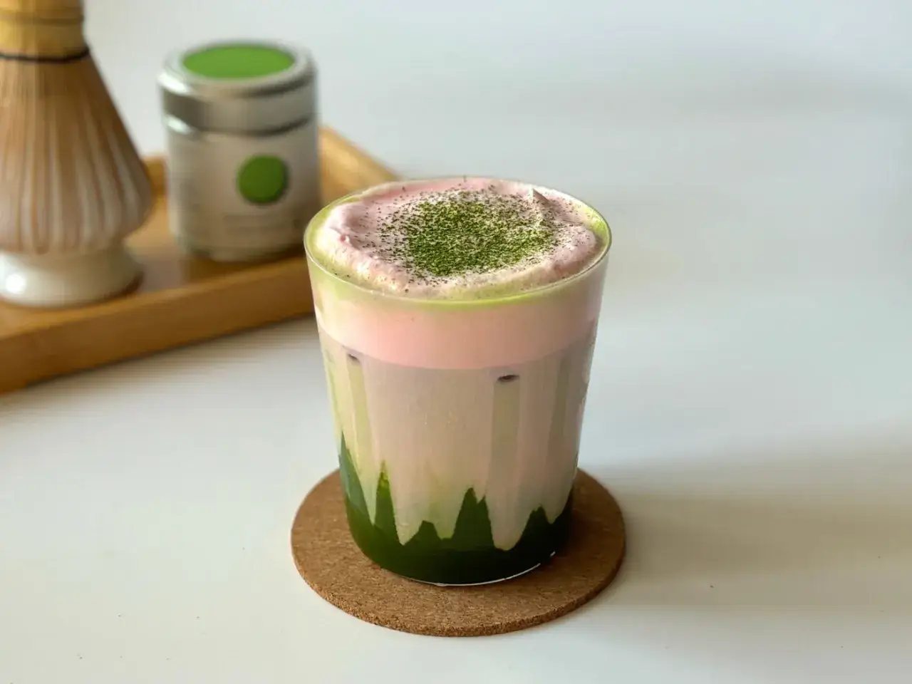 Un verre de matcha latte rose et vert, garni de poudre de matcha. Le matcha latte gout est délicieux.