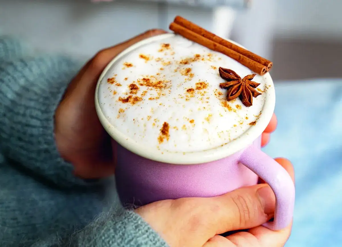 Mug de chai latte crémeux, saupoudré de cannelle et décoré d'une étoile de badiane et de bâtons de cannelle. Une boisson réconfortante aux multiples chai latte bienfaits.