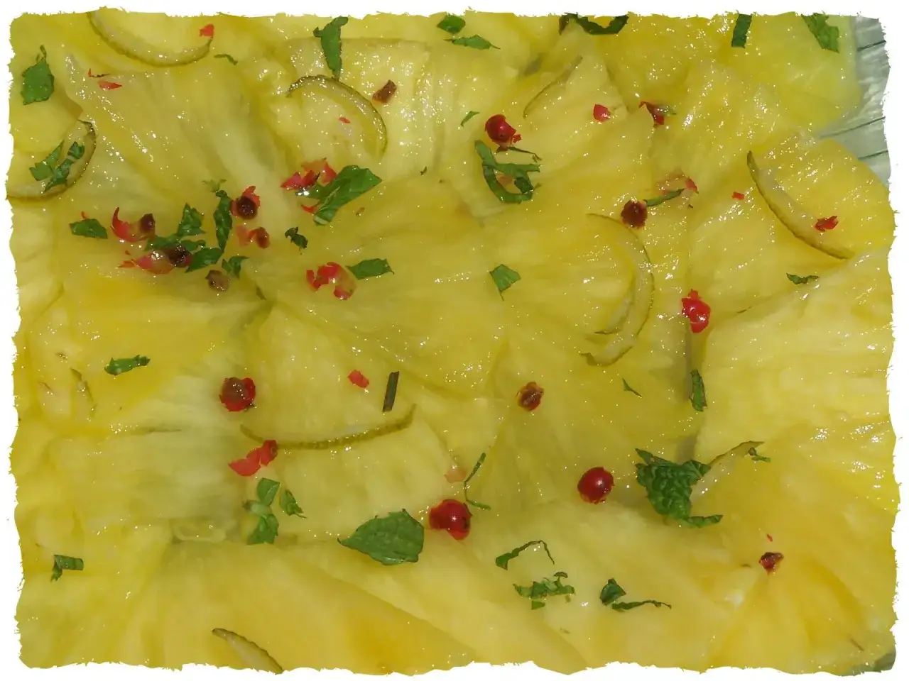 Carpaccio d'ananas frais, garni de menthe ciselée, de baies roses et de fines lamelles de citron vert. Un délice fruité et rafraîchissant.