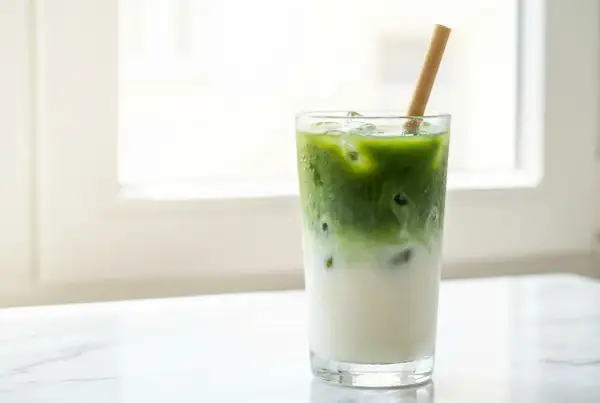 Un verre de matcha latte glacé avec une paille en bambou, parfait pour savourer son goût unique.