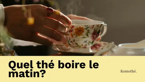 Une main ornée d'une bague saisit une tasse de thé fumante, ornée de fleurs. La question "Quel thé boire le matin?" invite à découvrir le plaisir d'une boisson matinale.