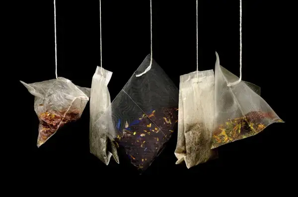 Cinq sachets de thé suspendus, révélant des mélanges variés de marc de thé et de fleurs séchées.