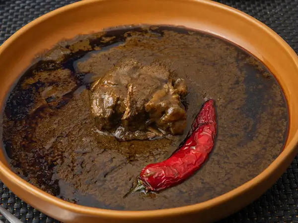 Un plat de mloukhia égyptienne, un ragoût de viande savoureux, servi avec un piment rouge séché dans un bol en terre cuite.